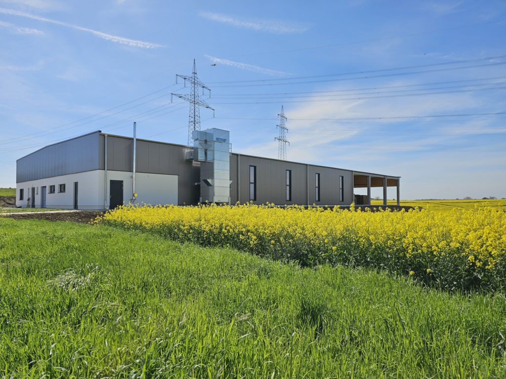 Blick über grüne Wiese und Felder auf das Firmengebäude von Weber Industrieverpackungen