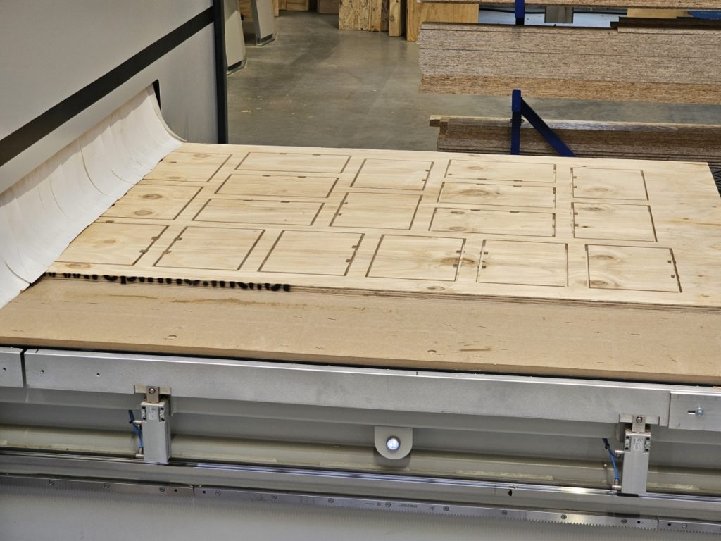 Platte mit Frästeilen / Holzzuschnitten aus der CNC-Maschine kommend